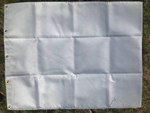 A gray canvas tent heat shield with metal grommets, laid out on a grassy surface.