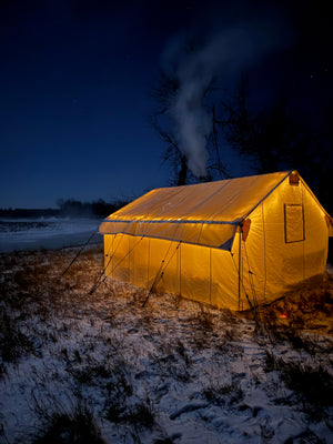 Yellow kite-like structure on a snowy landscape at night