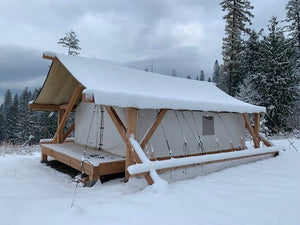 Heavy Duty Canvas Tent with snow-covered roof in a snowy forest