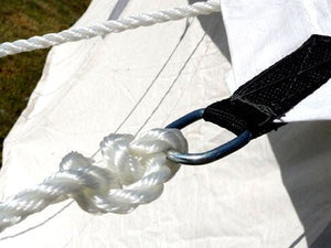 Close-up of a webbed D-ring attachment securing a white guy line to a canvas tent sidewall.