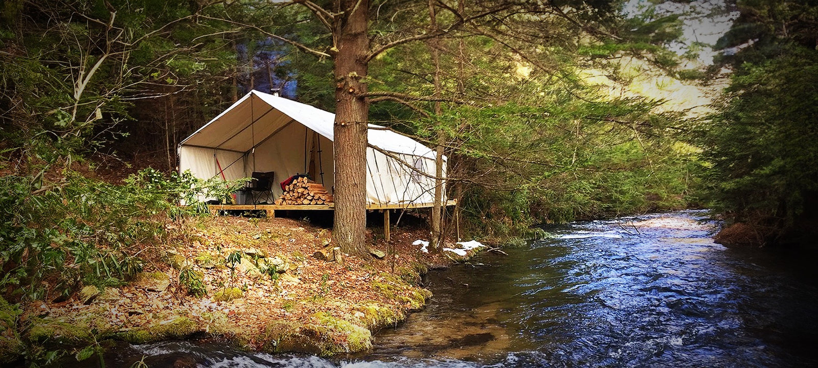 wall tent along the river in the woods