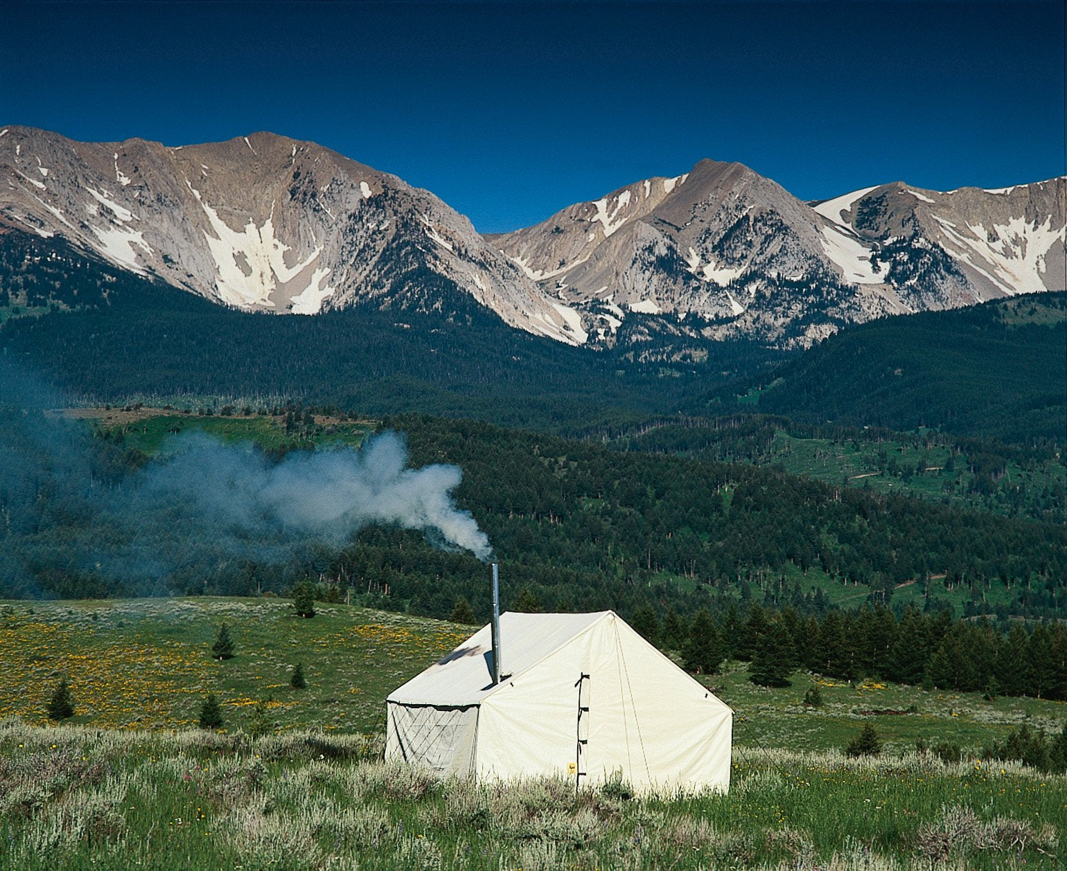 Outfitter Wall Tent with smoke coming out of stove pipe in front of Mountain Range